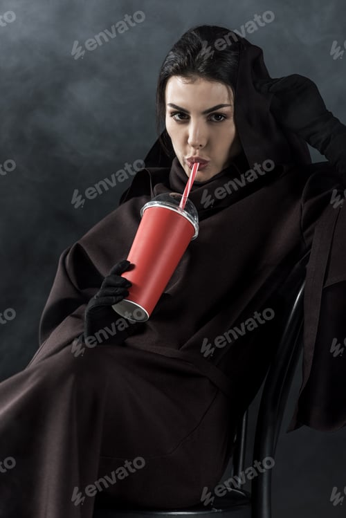 Preview: woman in death costume sitting on chair and drinking beverage on black