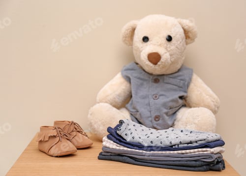 Preview: Teddy bear and stylish child clothes on table against light background