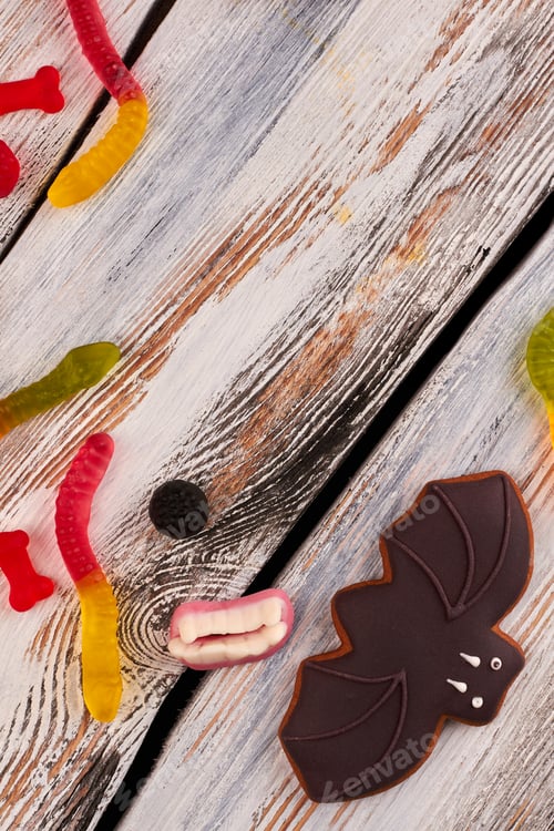 Preview: Bat cookie and jelly candies on wooden background.