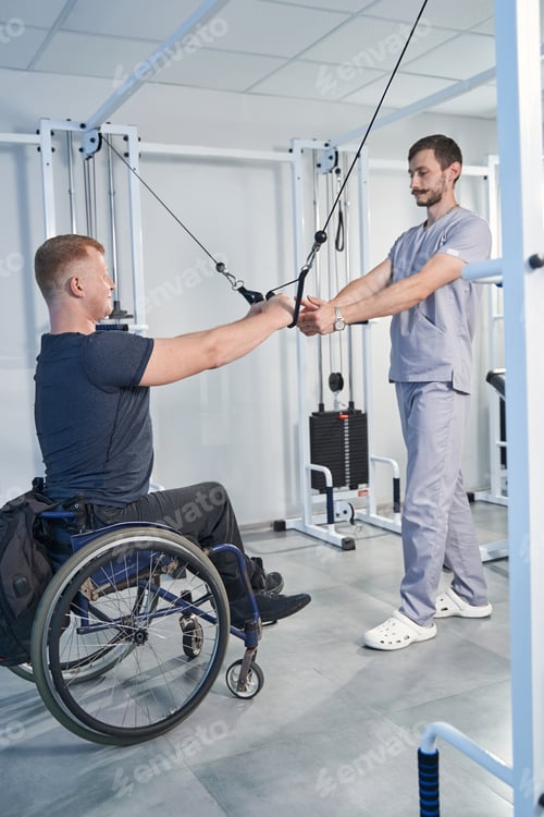 Preview: Young man pulling resistance cable in rehabilitation clinic