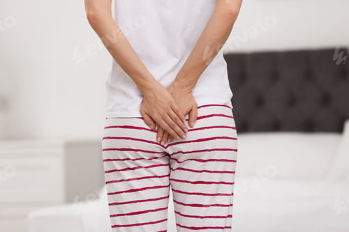 Preview: Young woman suffering from hemorrhoid in bedroom, closeup