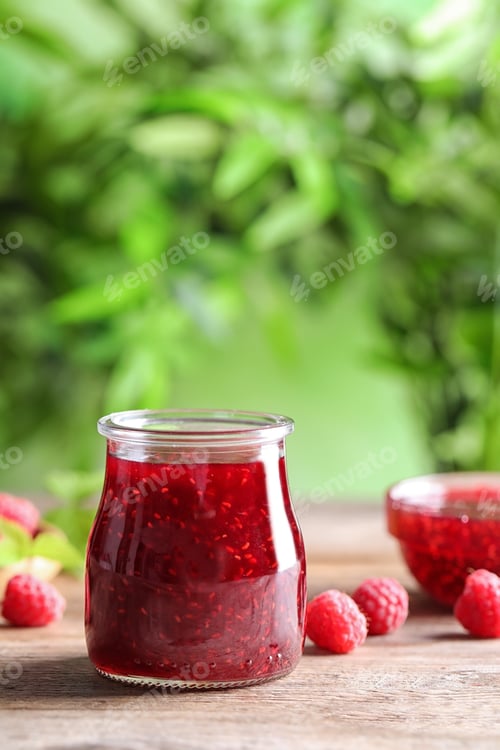 Preview: Glass jar of sweet jam with ripe raspberries on wooden table against blurred background