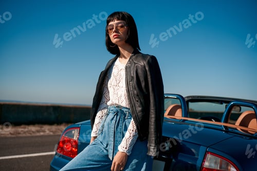 Preview: Close-up of young stylish woman with a haircut standing near roofless car