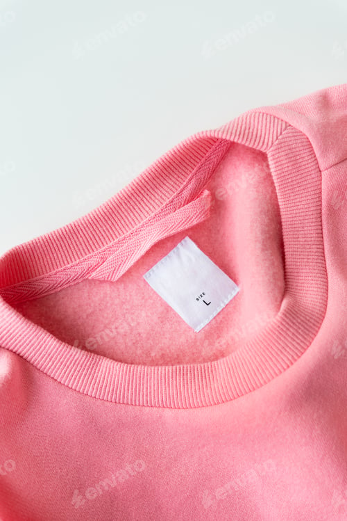 Preview: Clothing, fashion, shopping concept - closeup of a coral sweater tag. Place for inscription.