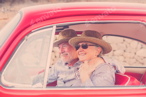 Preview: nice adult couple hug and love inside a red old vintage car parked on the road. smiles and fun