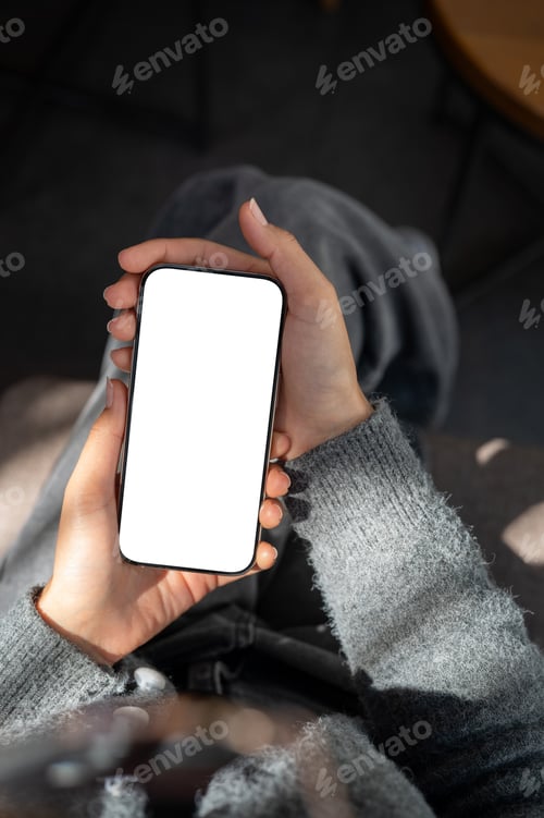 Preview: A close-up of a woman sitting indoors, sunlight streaming over her as she uses her smartphone.