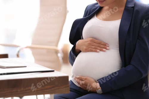 Preview: Young pregnant woman in suit at workplace, closeup. Space for text