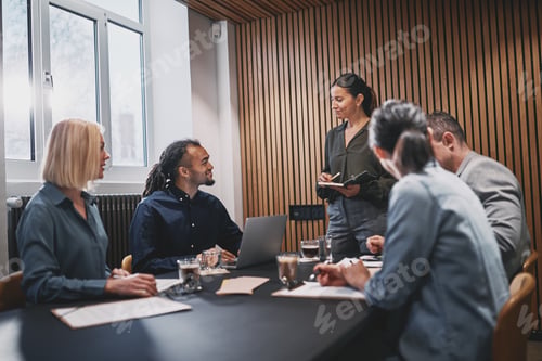 Preview: Smiling businesswoman meeting with colleageus in an office boardroom
