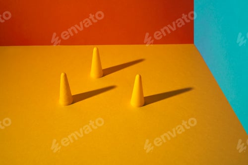 Preview: Three yellow cones with distance and hard shadow on a flat colored background. Blue Orange .