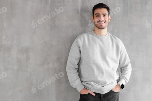 Preview: Young man in oversized sweatshirt isolated on textured gray wall background with copy space