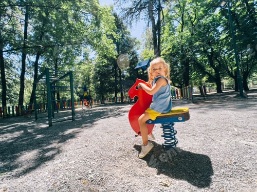 Preview: Little girl sitting on a swing-spring in the playground