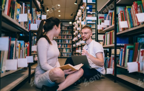 Preview: Student with laptop studying with friend in library