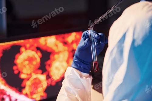 Preview: Scientist in white protective uniform works with coronavirus and blood tubes in laboratory