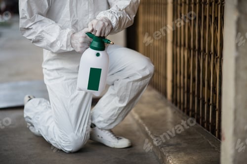 Preview: Man in protective suit and mask sprays disinfectant