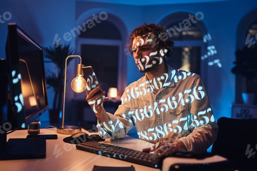 Preview: Office worker with mobile phone and computer in dark room