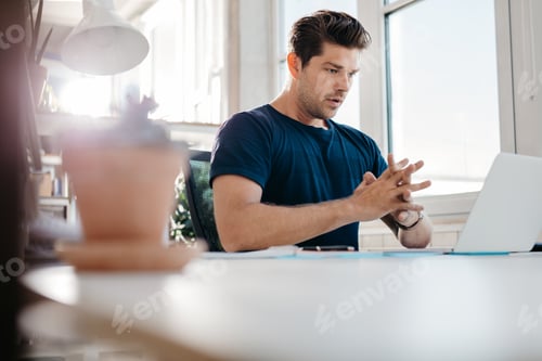 Preview: Young businessman looking at laptop in office