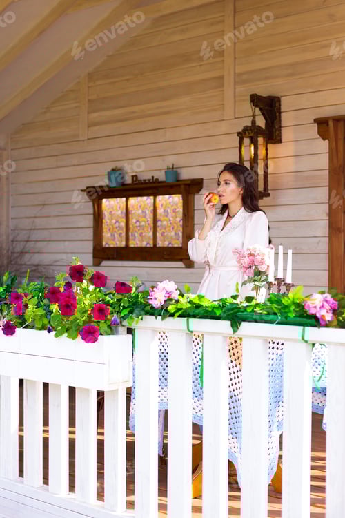 Preview: young woman on the terrace of her new house eating an apple