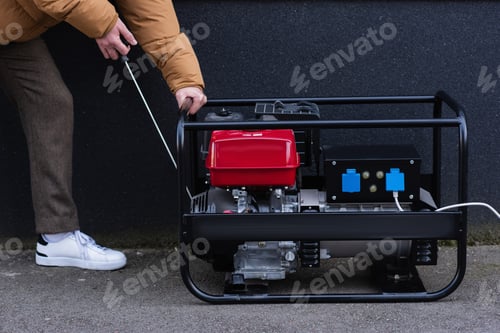 Preview: partial view of man starting electricity generator during energy blackout
