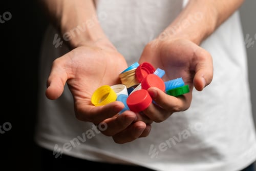 Preview: recycling of plastic, person holds color bottle caps