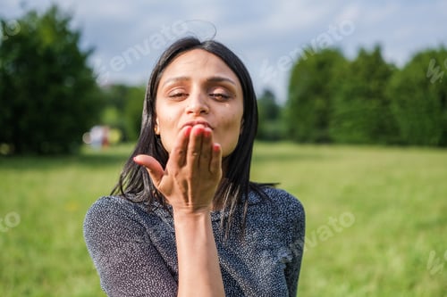 Preview: Young woman with brown eyes sending kisses to her friends.