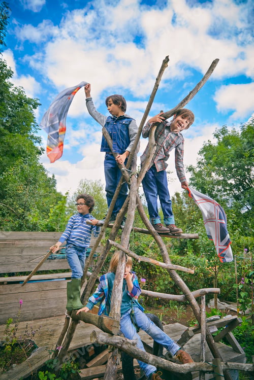 Preview: Four boys climbing on homemade climbing frame in garden
