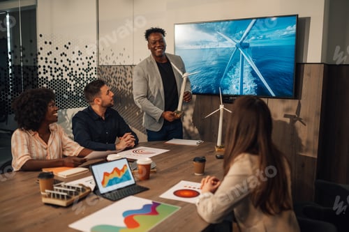 Preview: Diverse environmentalist with windmill having presentation with team.