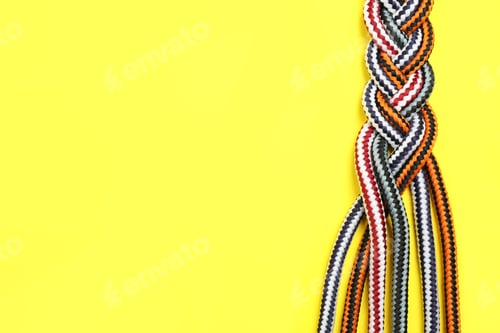 Preview: Top view of braided colorful ropes on yellow background, space for text. Unity concept