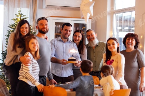 Preview: A big happy family at a festive table at home. An attractive young man with a cake