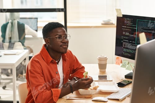 Young Man Eating Lunch at His Office Desk