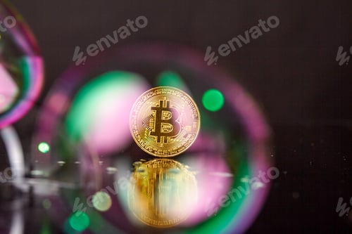 Preview: Golden bitcoin coin standing on a reflective desk surface.
