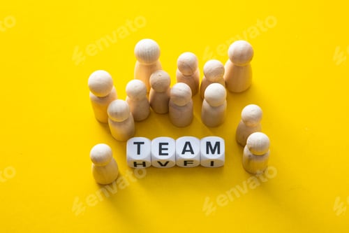 Preview: Carved wooden figurines arranged near the word team on the yellow background