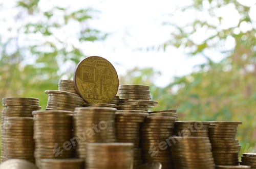 Preview: Big amount of bitcoin stacks on blurred green trees background close up
