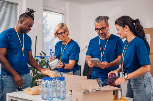 Preview: Diverse volunteers working in a charity donation center and packing clothes and food