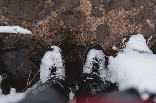 Preview: Hiking shoes covered with snow by the water