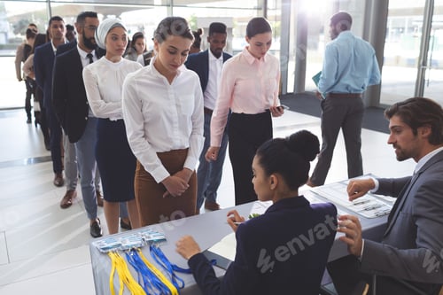 Preview: Side view of diverse business people checking in at conference registration table in lobby office