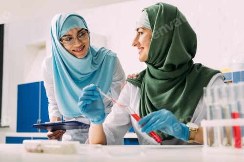 Preview: smiling female muslim scientists in hijab with test tube and pipette during experiment in chemical