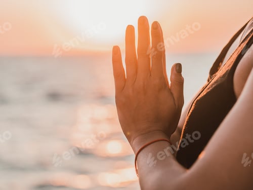 Preview: Pleasant woman makes greeting to the sun at sunrise on sea coast. Hands in namaste. Yoga