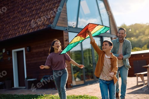 Preview: Happy boy flying a kite with his parents outdoors.