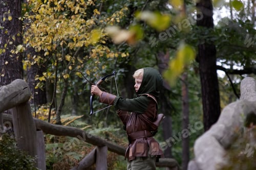 Preview: A boy in a medieval costume holding a bowstring against a forest background
