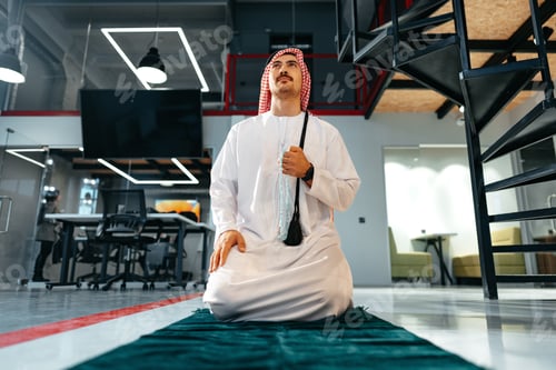 Preview: Young arab muslim man praying in office on carpet