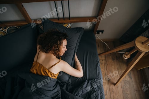 Preview: Woman sleeping on side on bed at home