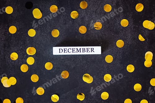 Preview: Word December and golden confetti lying on dark black background