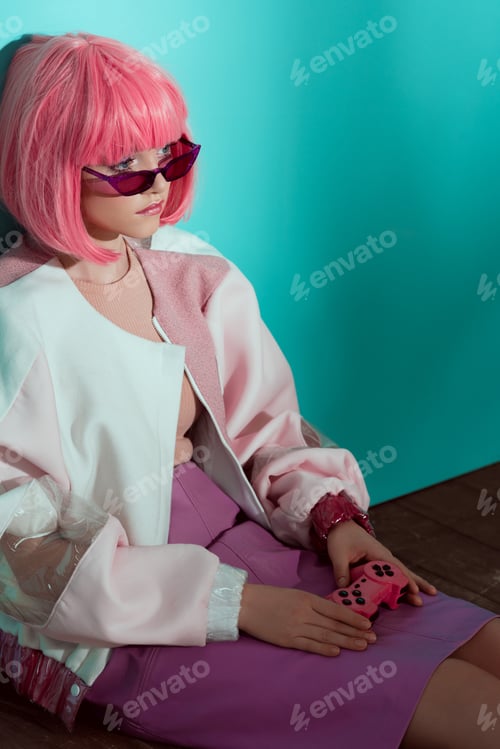 Preview: high angle view of pretty stylish girl in pink wig holding joystick, sitting on floor and looking