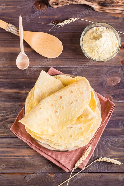 Preview: Homemade corn mexican tortillas wrap on a board on the table. Top and vertical view
