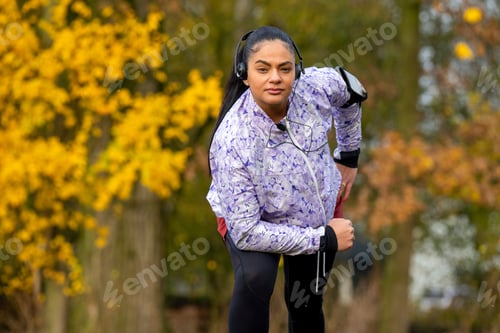 Preview: Healthy woman stretching listening to music at the public park