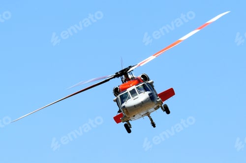 Preview: Red and white helicopter flying in a clear blue sky