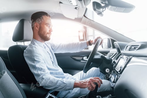 Preview: Side view of young handsome man in formal clothes that sitting in brand new automobile
