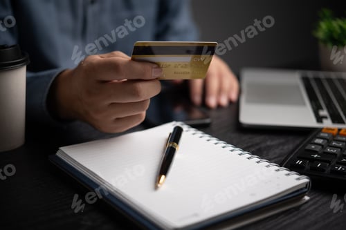 Preview: Business man holding credit card and using laptop.