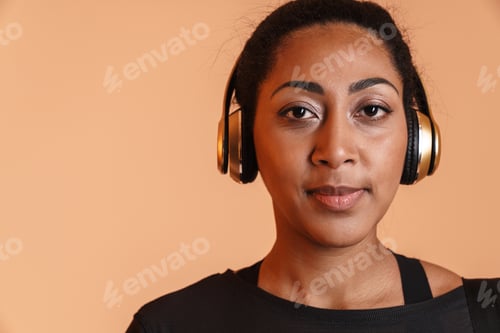 Preview: Pleased african american woman in headphones looking at camera