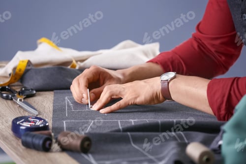 Preview: Tailor working at table in atelier, closeup